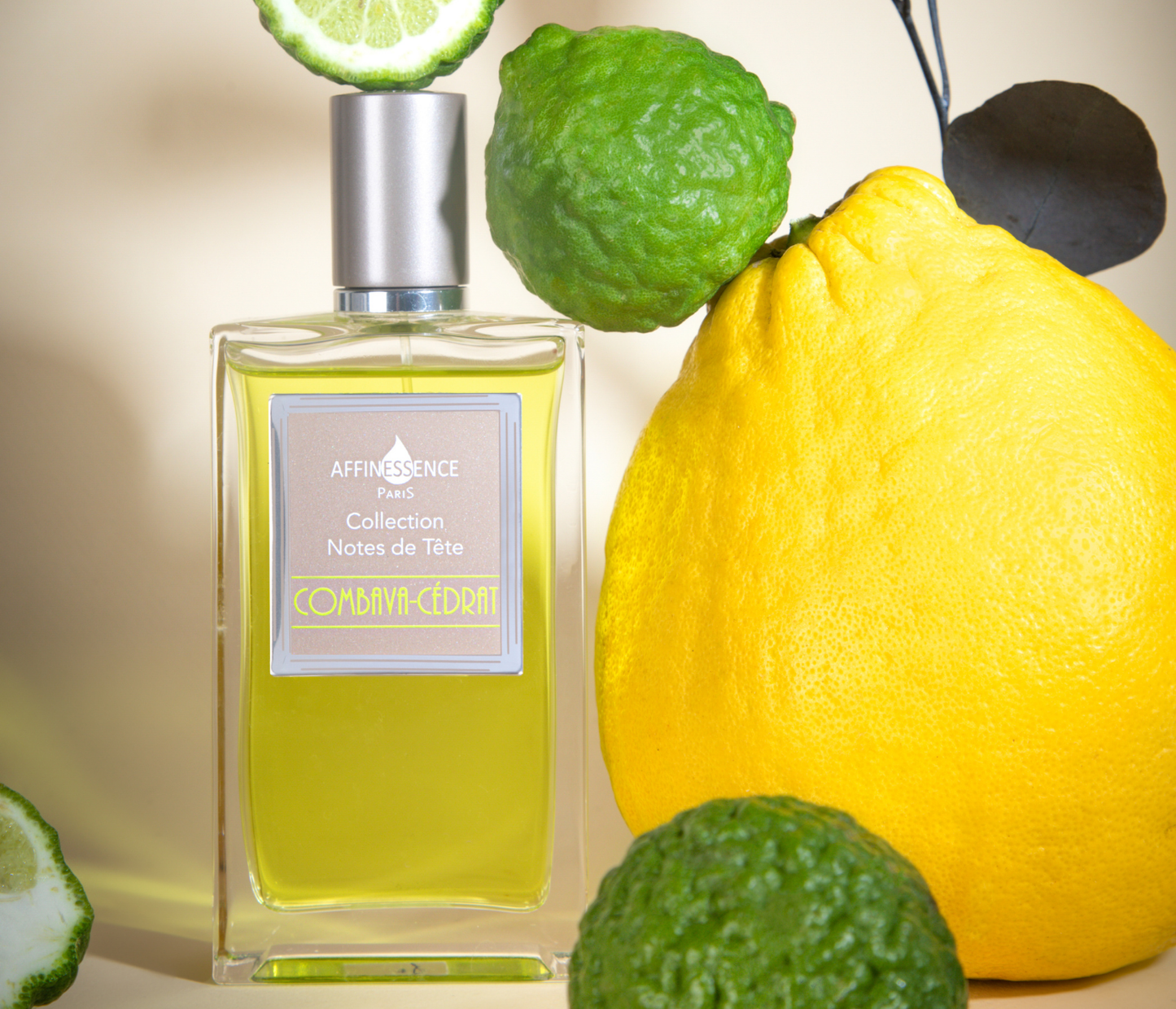Affinessence Commix-Cedron perfume bottle next to citrus fruits on a neutral background.