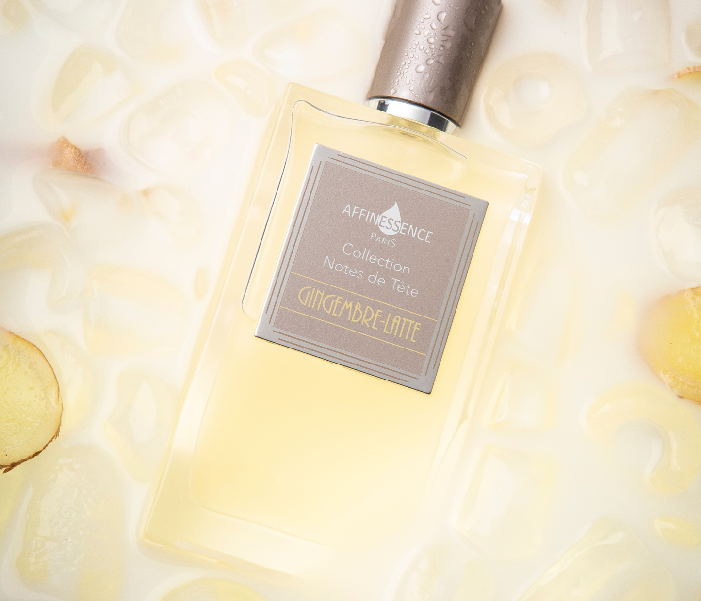 Affinessence Gingembre Latte perfume bottle with silver cap and label on a soft yellow background with ice melting and slices of ginger.